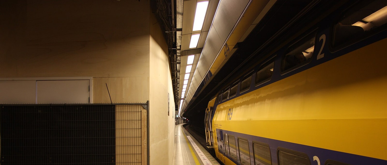 A yellow NS train at the platform of an underground station