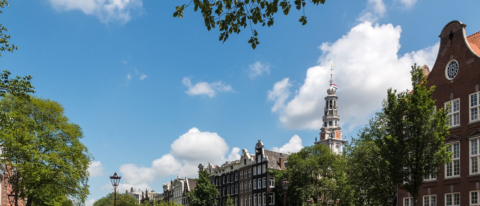 An Amsterdam canal with gabled houses and a church tower behind
