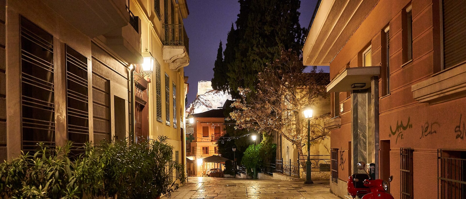 A Plaka street at dusk, its lamps lit