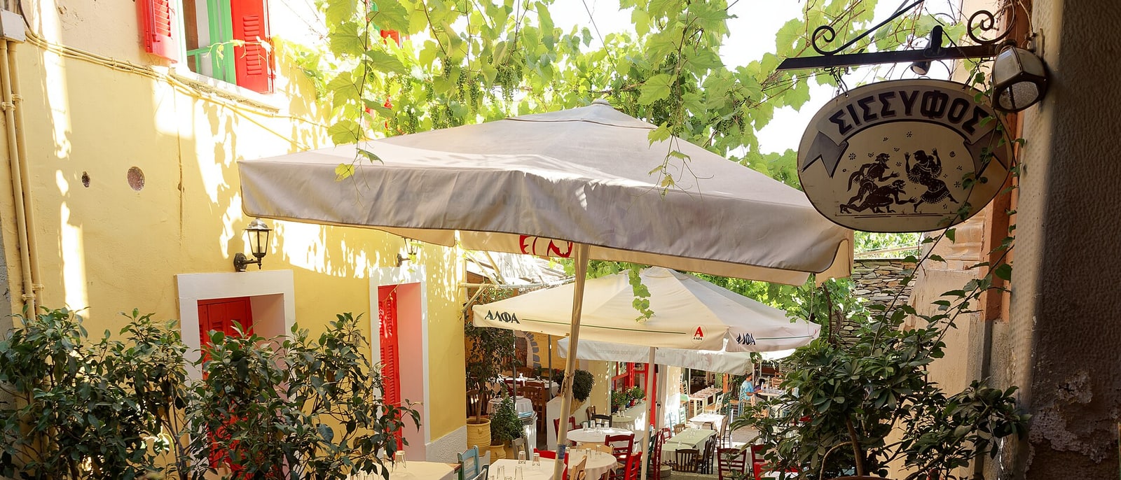 La terraza de una taberna con parra y sombrillas, en Plaka