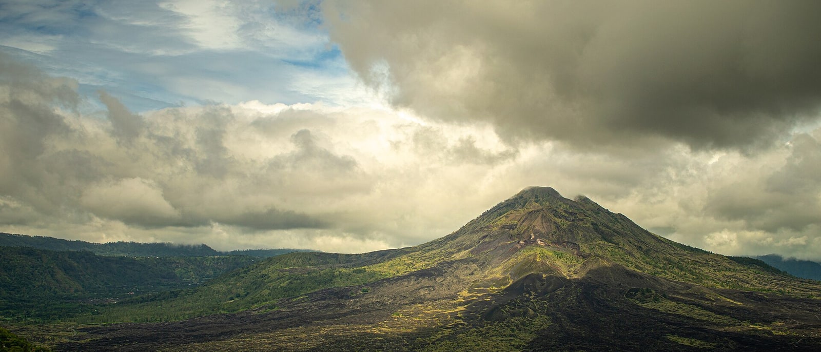 Mount Batur, its dark lava slope under a heavy sky