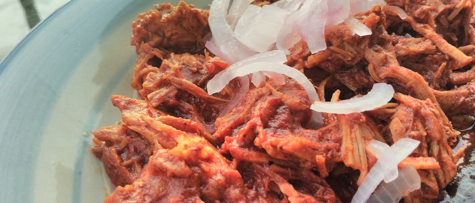 A plate of cochinita pibil topped with pickled red onion