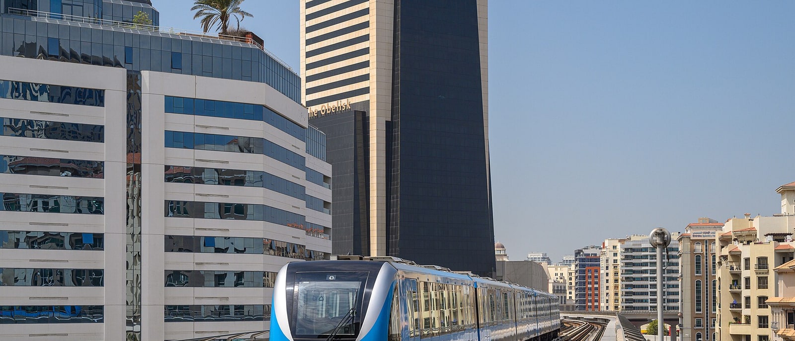 A Dubai metro train on its viaduct, among the towers