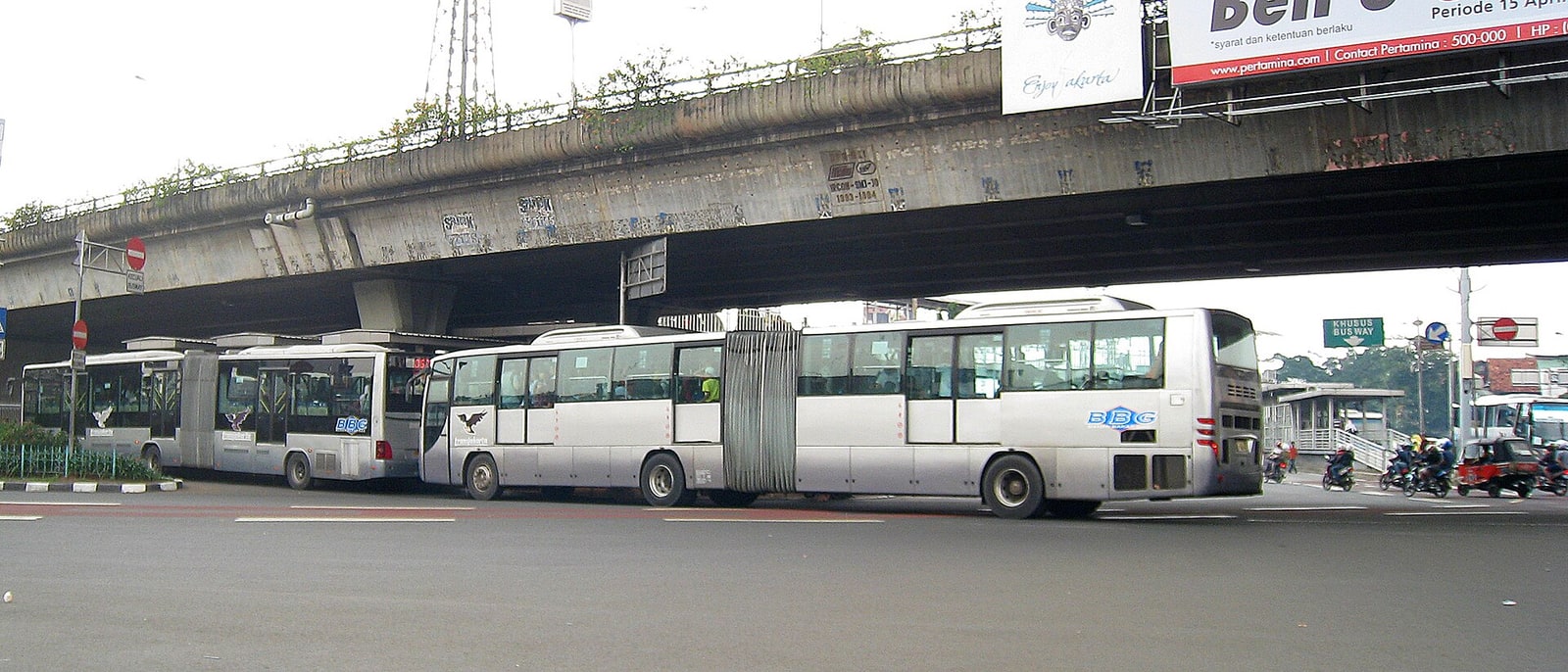 A TransJakarta articulated bus under a flyover