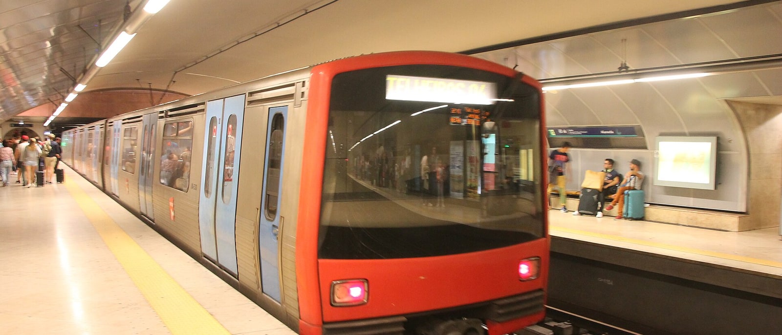 A red Lisbon metro train pulling into the station