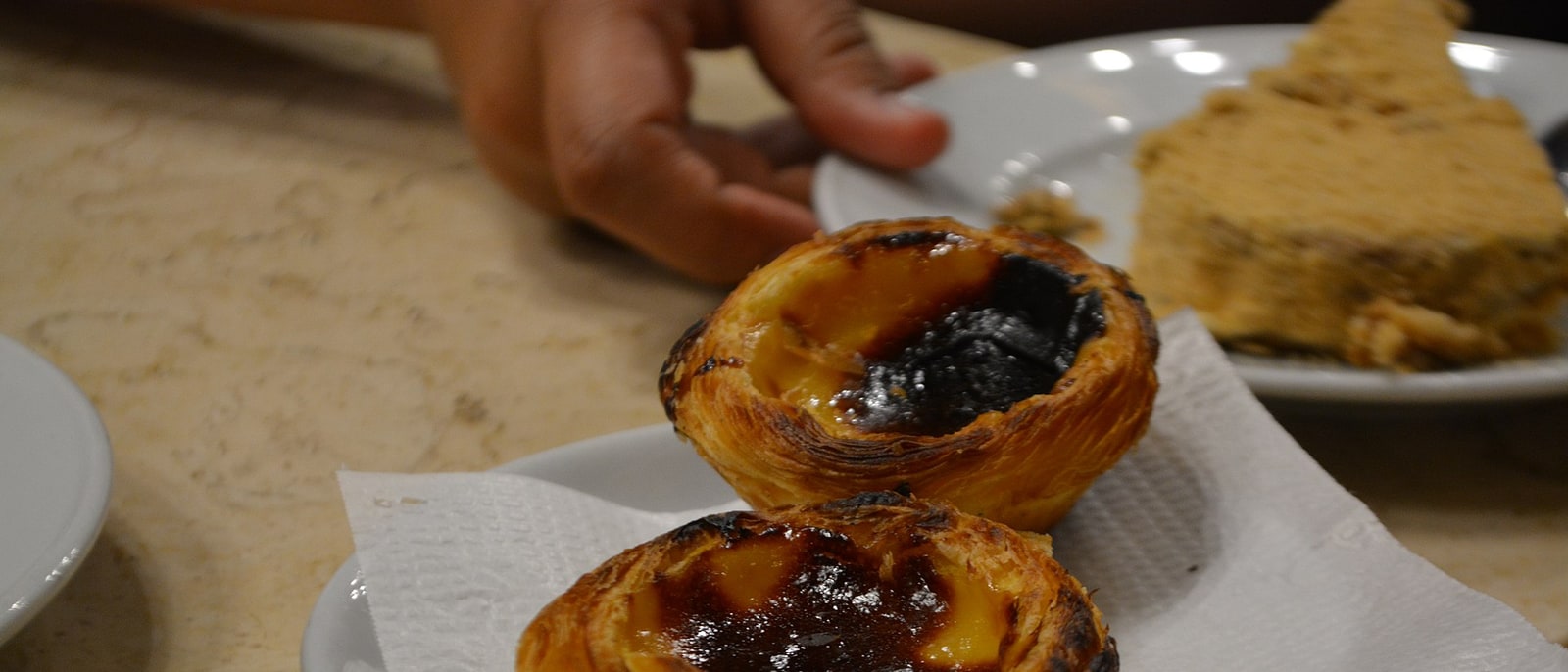 Two pastéis de nata on a plate, dusted with cinnamon