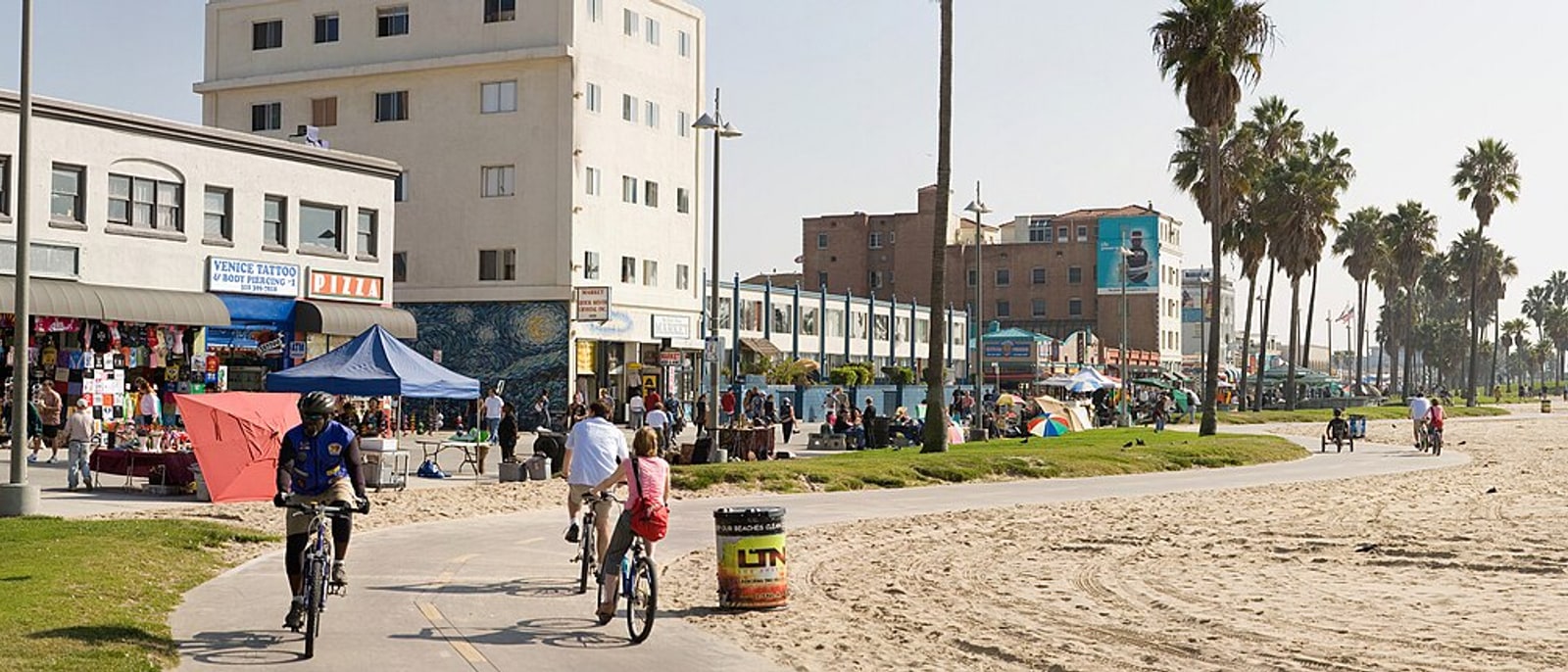 The Venice Beach boardwalk with cyclists, palms and sand alongside