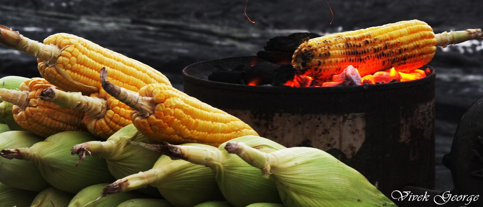 Corn cobs roasting on a brazier by the sea