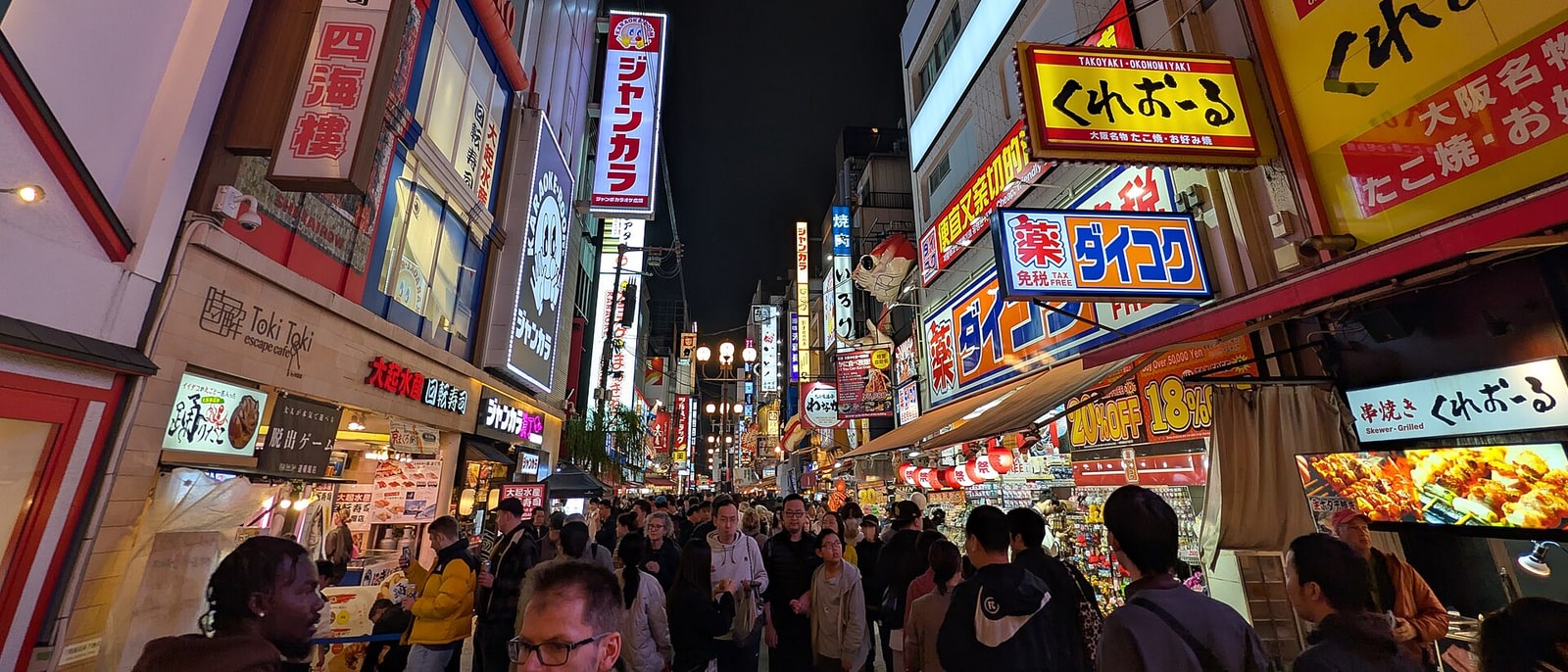 A Dotonbori street at night, its illuminated signs lit up