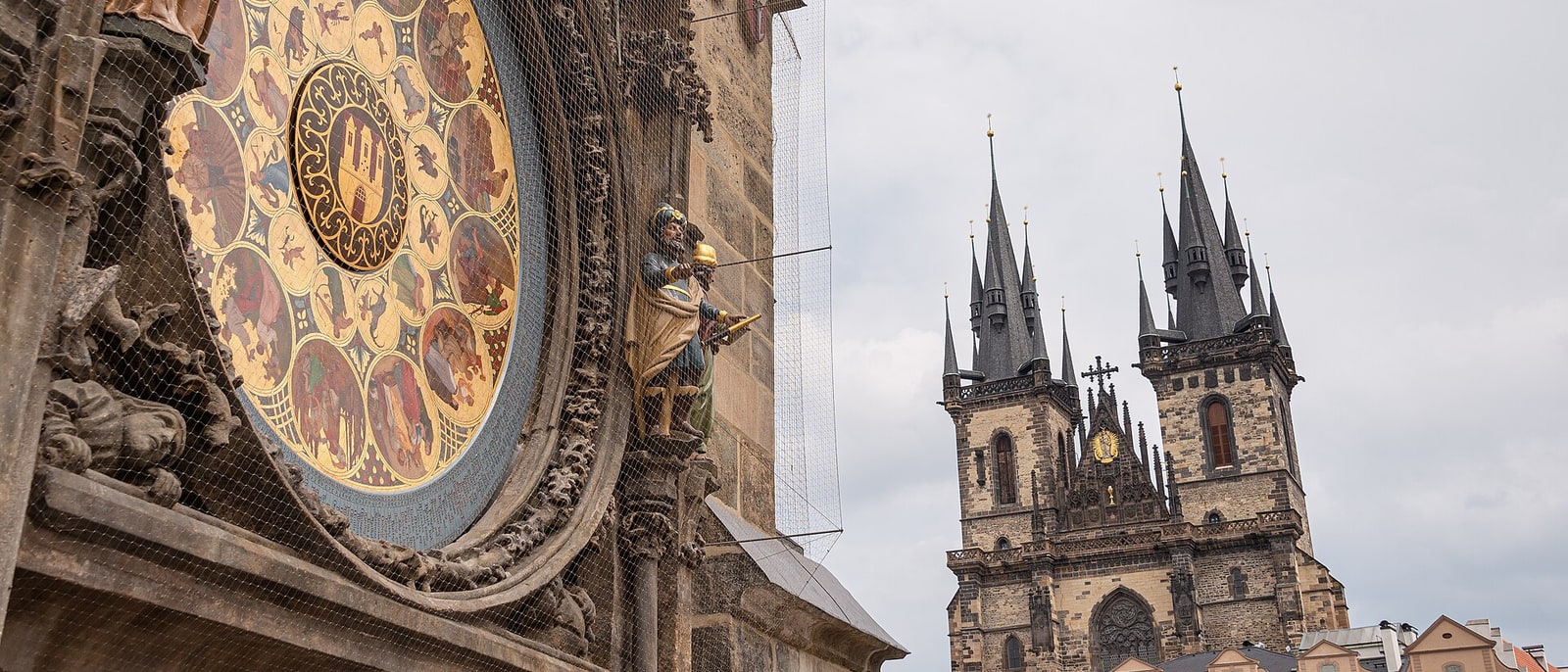 La esfera del reloj astronómico de cerca, con las torres de la iglesia de Týn detrás