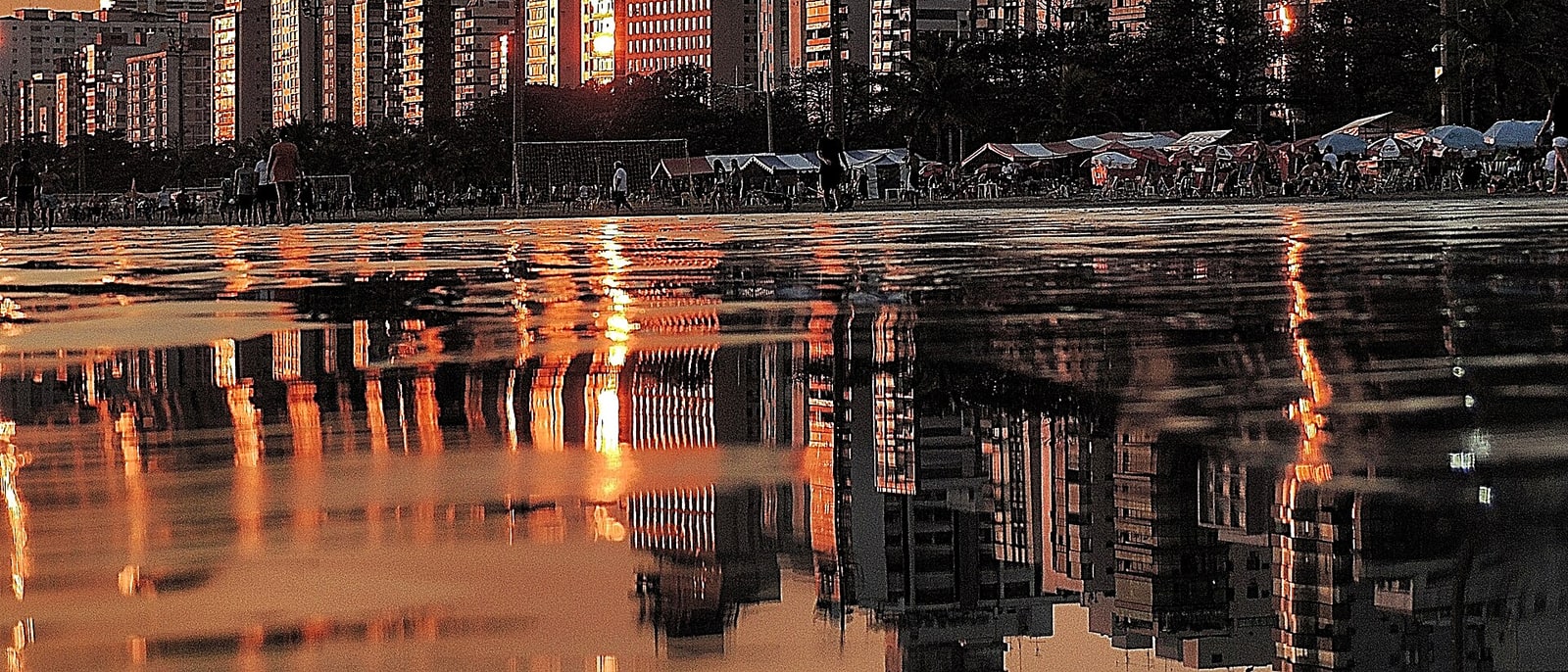 Los edificios de Santos reflejados en la arena mojada al atardecer