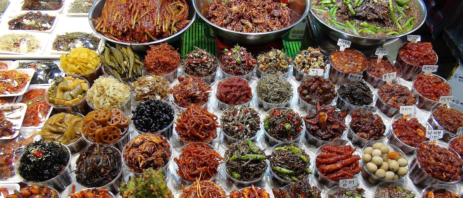 Un puesto de mercado con decenas de banchan en cuencos