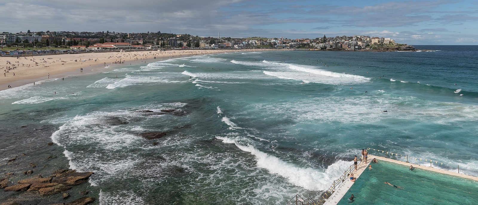 A Sydney beach with its ocean pool and the surf breaking