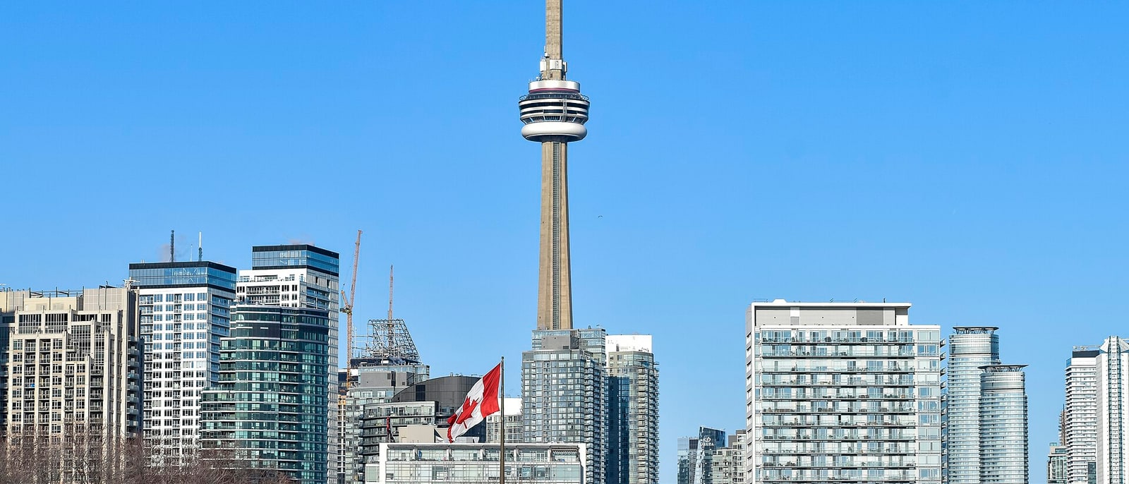 The CN Tower rising above the downtown towers, a Canadian flag in front