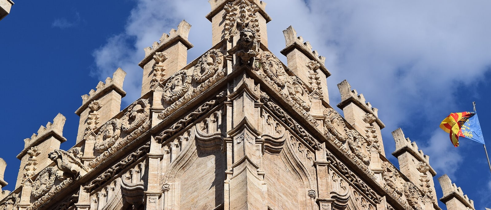 The Gothic pinnacles of the Silk Exchange against the sky, the Valencian flag flying